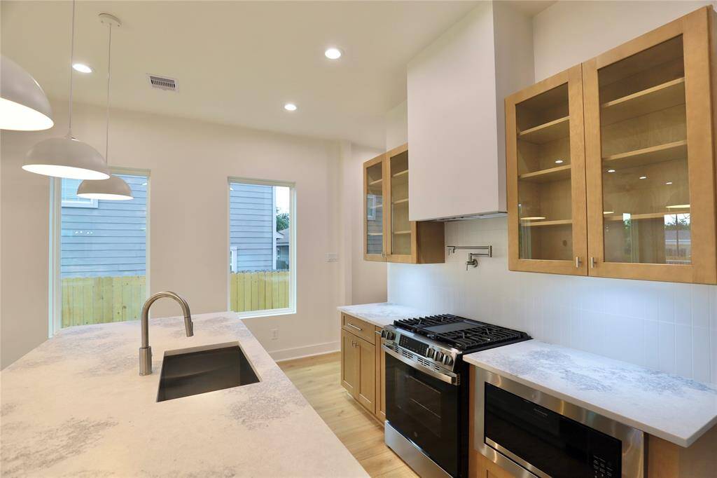 The balanced combination of sleek glass-front and warm wood-style cabinets adds both elegance and warmth to this gourmet kitchen.
