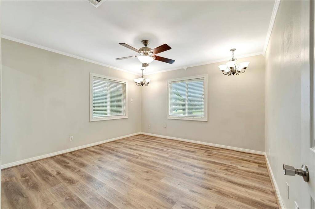 Bright primary bedroom featuring large windows, a sleek ceiling fan, and lighting.