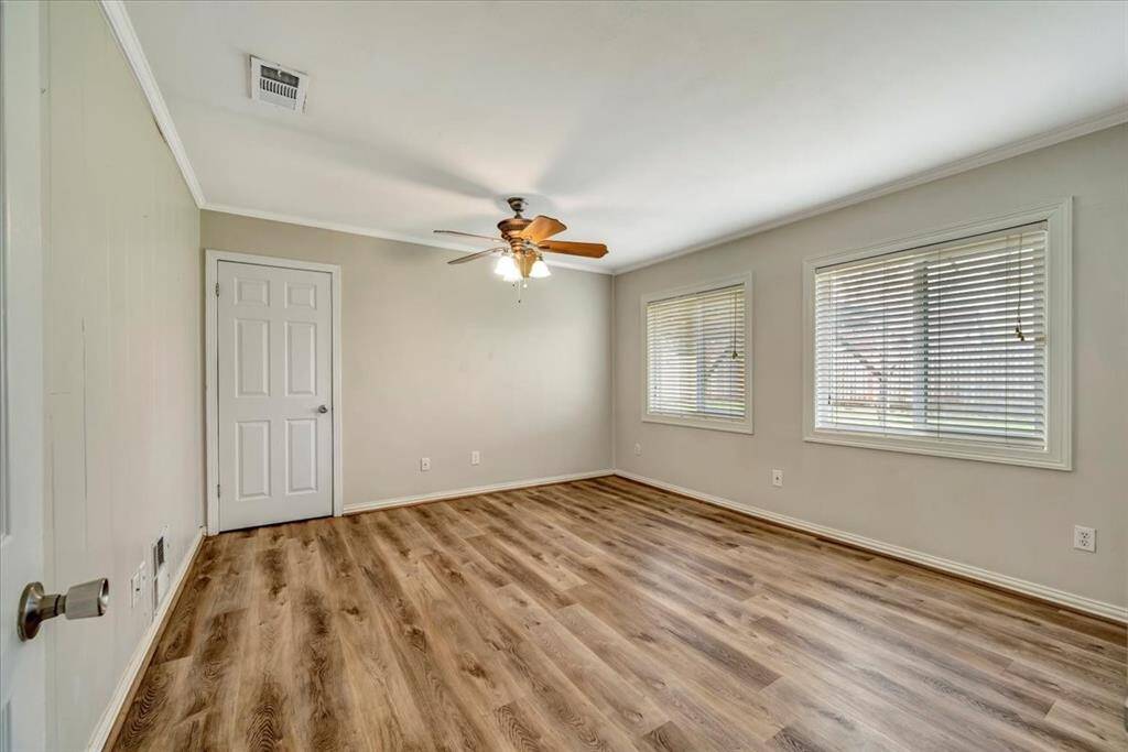 Spacious and inviting bedroom with abundant natural light, featuring stylish flooring and a modern ceiling fan.