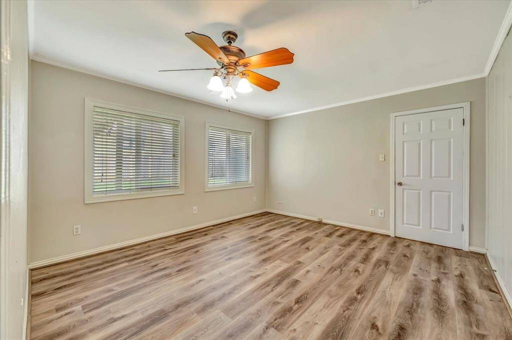 This inviting room boasts elegant flooring, neutral walls, and abundant natural light from large windows with blinds. A stylish ceiling fan enhances comfort.
