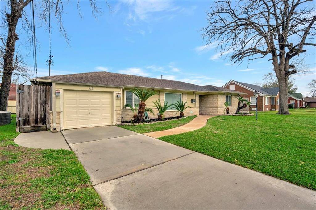 Features a one-car garage and a paved driveway. The exterior has a mix of stone and siding, with a welcoming walkway leading to the entrance.