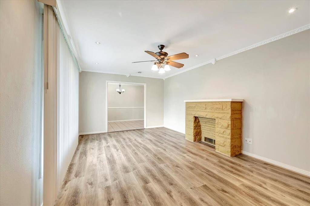 Discover a spacious living area with a modern floor, ceiling fan, and inviting fireplace. Enjoy abundant natural light from large window, and seamlessly transition to the tiled dining area.