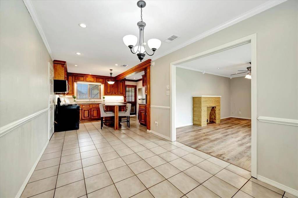 Discover a spacious kitchen and dining area with tiled floors, wooden cabinetry, and a modern light fixture. Seamlessly flowing into the living room.