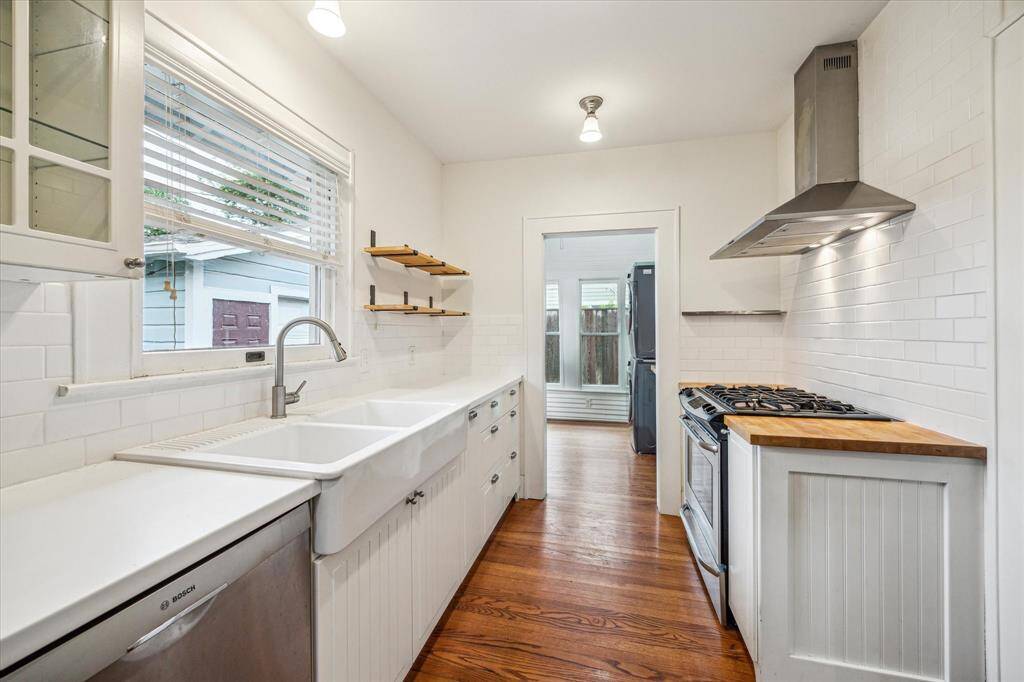 An additional view of the Kitchen reveals its seamless connection to a designated laundry room and convenient back door access. The space is filled with abundant natural light and features charming period light fixtures, enhancing its welcoming ambiance.