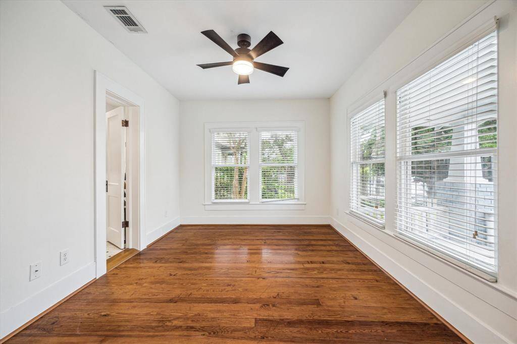 The Front Bedroom features beautiful hardwood floors, contemporary ceiling fan, and four generously sized windows, each adorned with shades for your comfort and convenience.