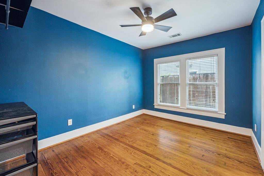 The Rear Bedroom boasts beautiful hardwood floors, a modern ceiling fan, and an abundance of natural light, enhanced by windows complete with convenient shades.