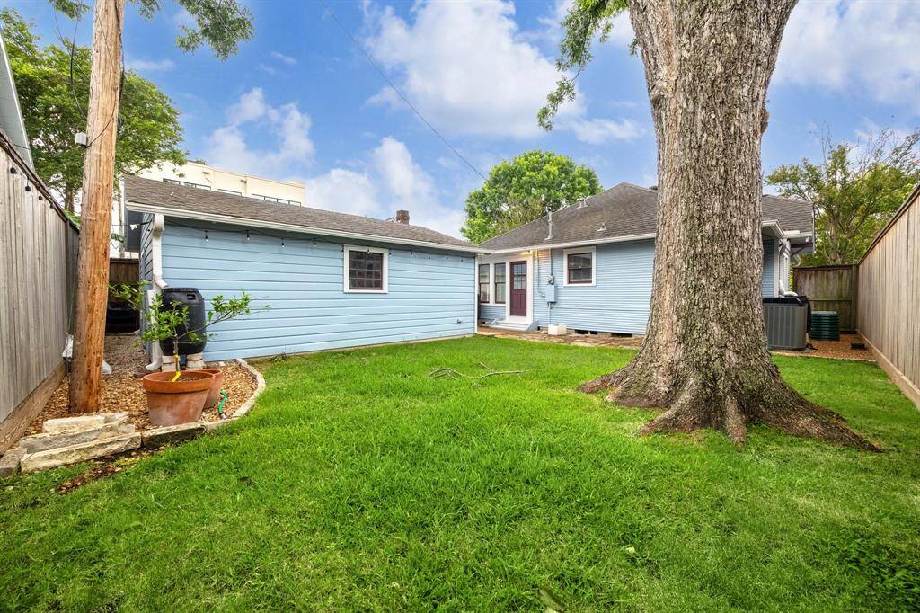 Expansive backyard, showcasing magnificent pecan tree that adds both grandeur and natural beauty. Photo also depicts path to additional room in the garage, offering flexible space for storage or hobbies.