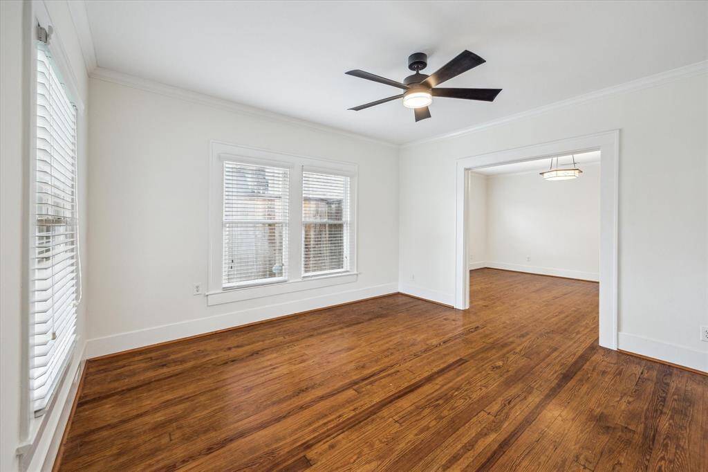 Another view of the Living Room showcases the abundance of windows that fill the space with natural light, accentuating the rich hardwood floors and fresh paint. The open layout seamlessly connects to the Dining Room, perfect for entertaining and modern living.
