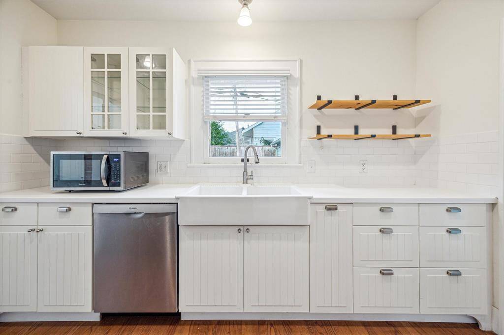 The charming Kitchen showcases an elegant apron double sink, beadboard cabinets adorned with contemporary hardware, and a picturesque window perfectly positioned above the sink, adding a delightful touch to the space.