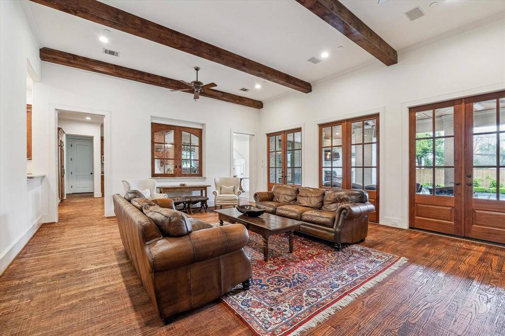 The family room features a distinctive interior window partition that opens to the kitchen, framed in rich wood to match the nearby doors. This architectural element allows for visual connection and light flow between the two spaces while maintaining separation, adding both charm and functionality to the layout.