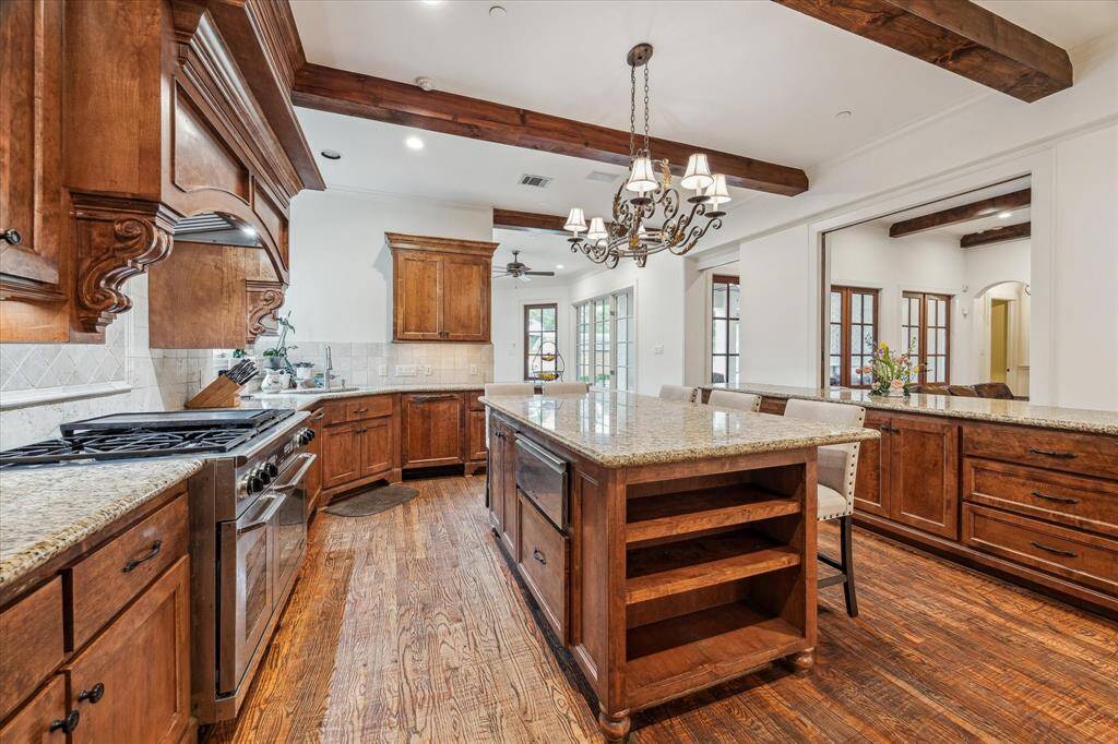 This kitchen is equipped with a high-performance double oven and a built-in warming drawer, ideal for cooking and entertaining. Expansive granite countertops offer generous workspace along the perimeter and center island, making food prep and serving efficient and convenient. The layout is thoughtfully designed to accommodate multiple users with ease.