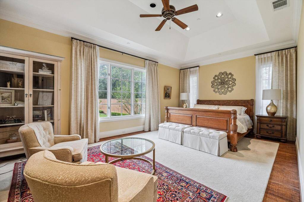 This first-floor primary bedroom features high vaulted ceilings and large windows that allow plenty of natural light to fill the space. The room is spacious and has an open layout with direct views of the backyard. Multiple windows provide both light and outdoor views, creating a bright and inviting atmosphere.