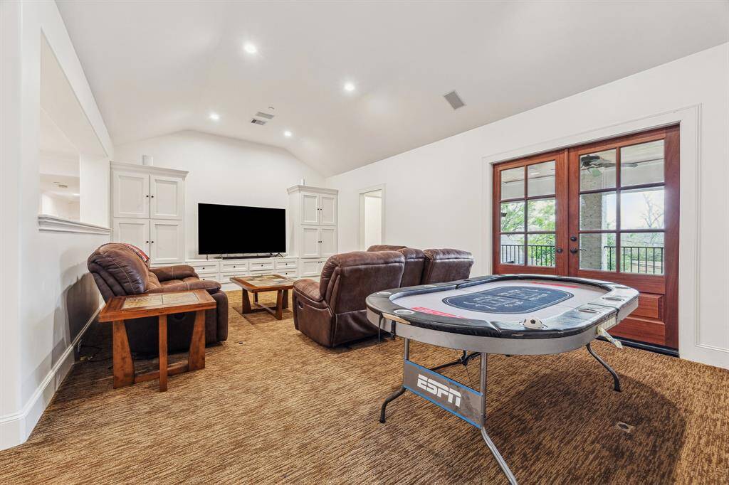 This spacious game room offers direct access to the second-floor balcony/patio, includes a built-in bar, and features generous storage with custom cabinetry and shelving. Ideal for entertaining or relaxing.