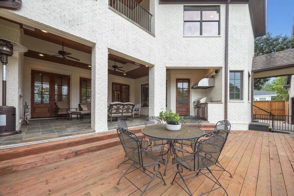 This wooden deck is situated just off the back of the house and offers a spacious area for outdoor living. It is slightly elevated with steps leading down to the yard and provides easy access to the covered patio and outdoor kitchen.