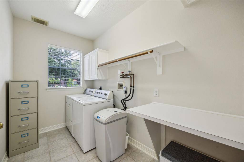 The spacious laundry room offers both functionality and convenience, featuring ample cabinetry for storage and countertop space for folding. Well-lit and thoughtfully designed, it provides an efficient workspace that makes household chores easier. Located on the upper floor for added ease, this laundry area blends practicality with a clean, organized aesthetic.