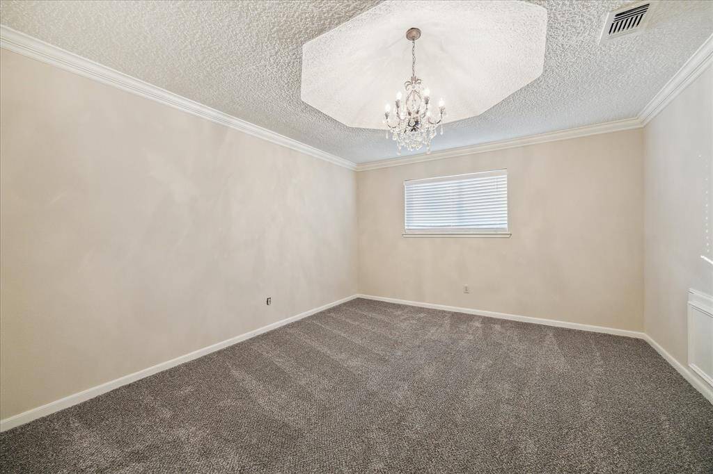 Upstairs bedroom features crown molding, a central chandelier, and plush new carpeting.