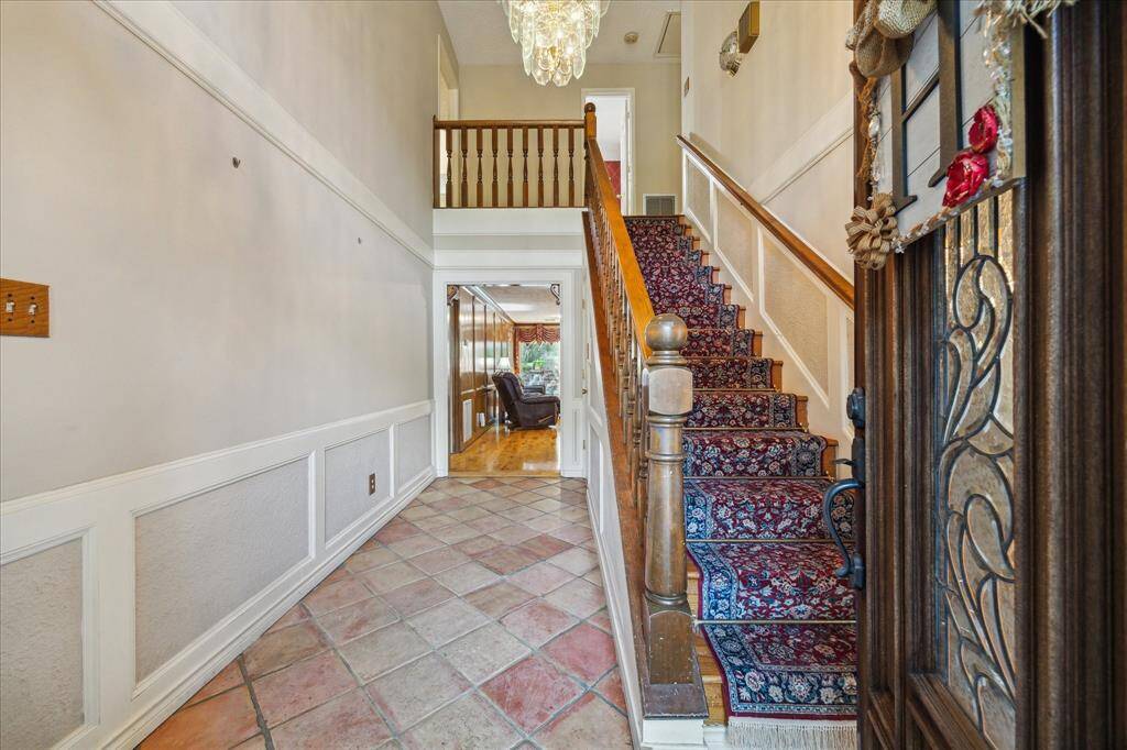 Welcoming foyer, bright and airy, with saltillo tiled flooring and wood paneling leading to a cozy living area. Perfect for those who appreciate classic design elements.