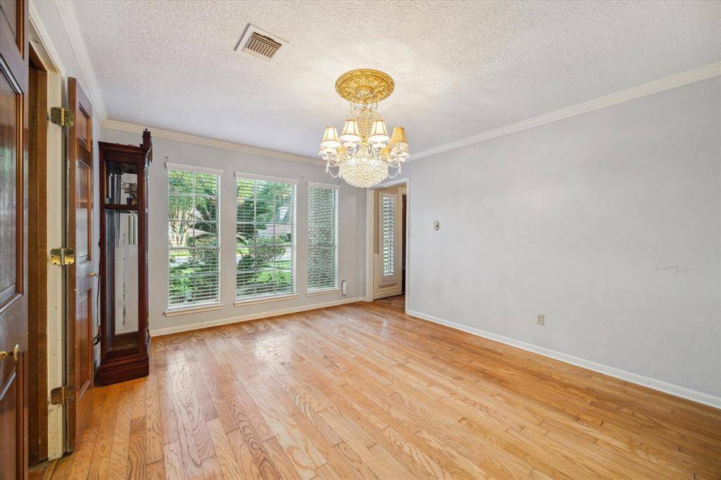 This formal dining room features hardwood floors, large windows with shutters, and a central chandelier, creating a bright and elegant space.