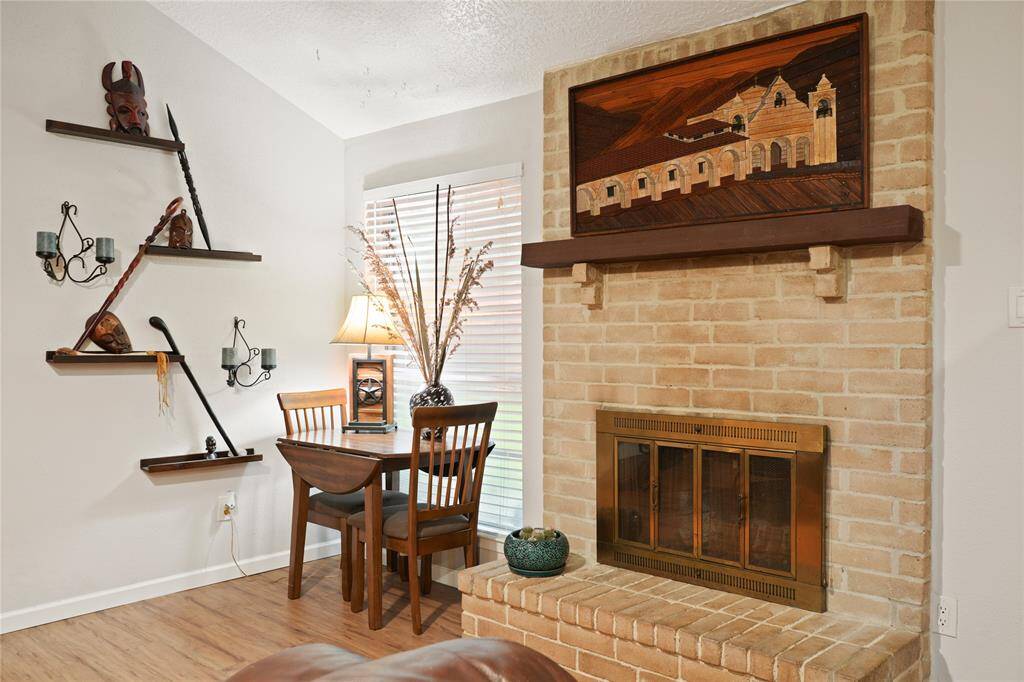 This cozy living space features a charming brick fireplace with a decorative mantel. The warm wood flooring adds to the inviting ambiance.