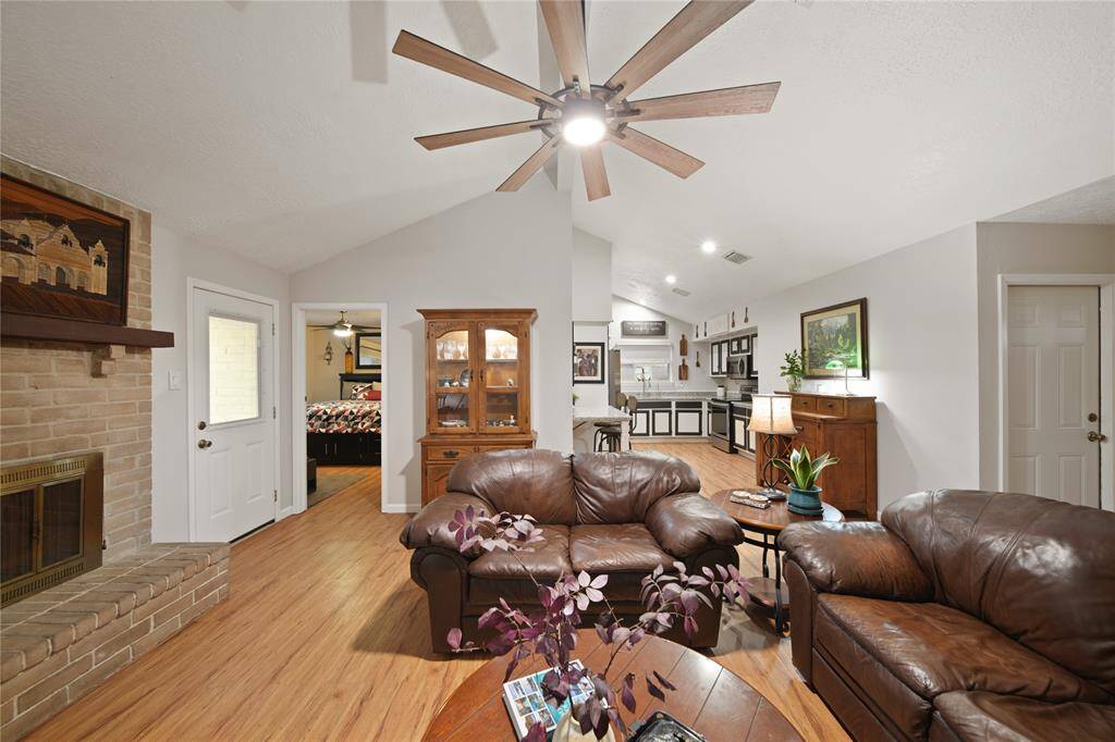 Step into this charming living area, where a vaulted ceiling and sleek modern ceiling fan create an airy ambiance. The space seamlessly connects to an open kitchen featuring a stylish breakfast bar, perfect for casual dining and entertaining.
