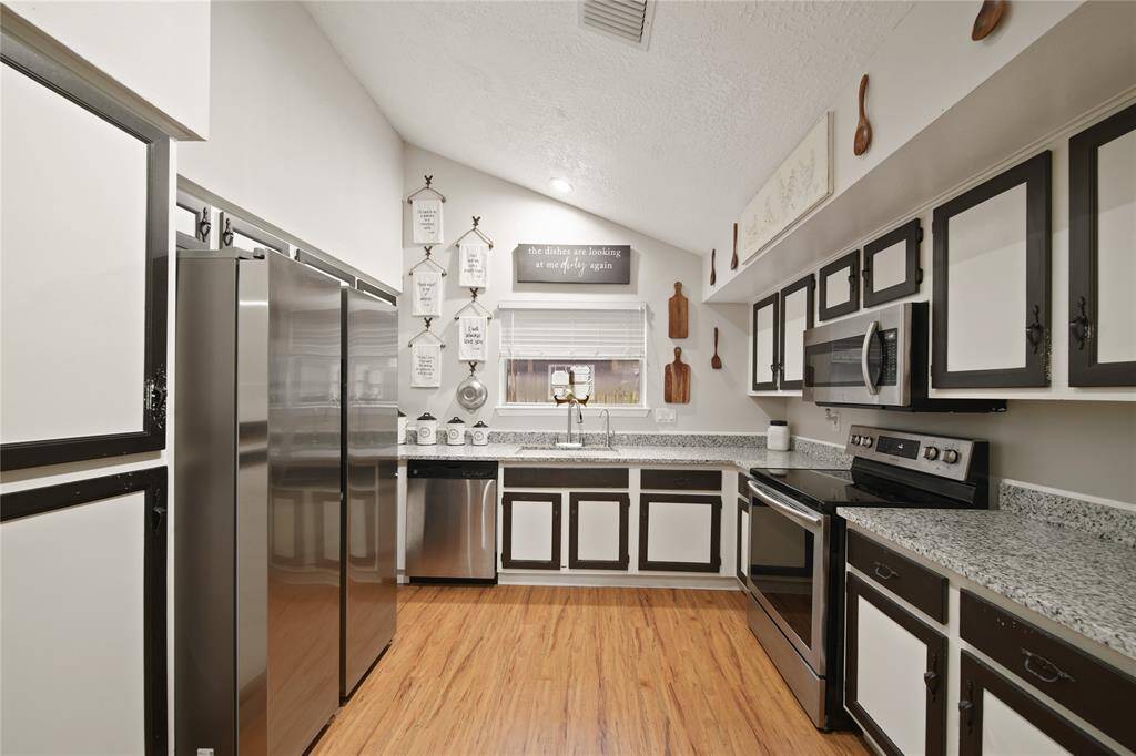 This kitchen features stainless steel appliances and granite countertops that combine style with functionality. The two-tone black and white cabinetry adds a chic, contemporary flair to the space.