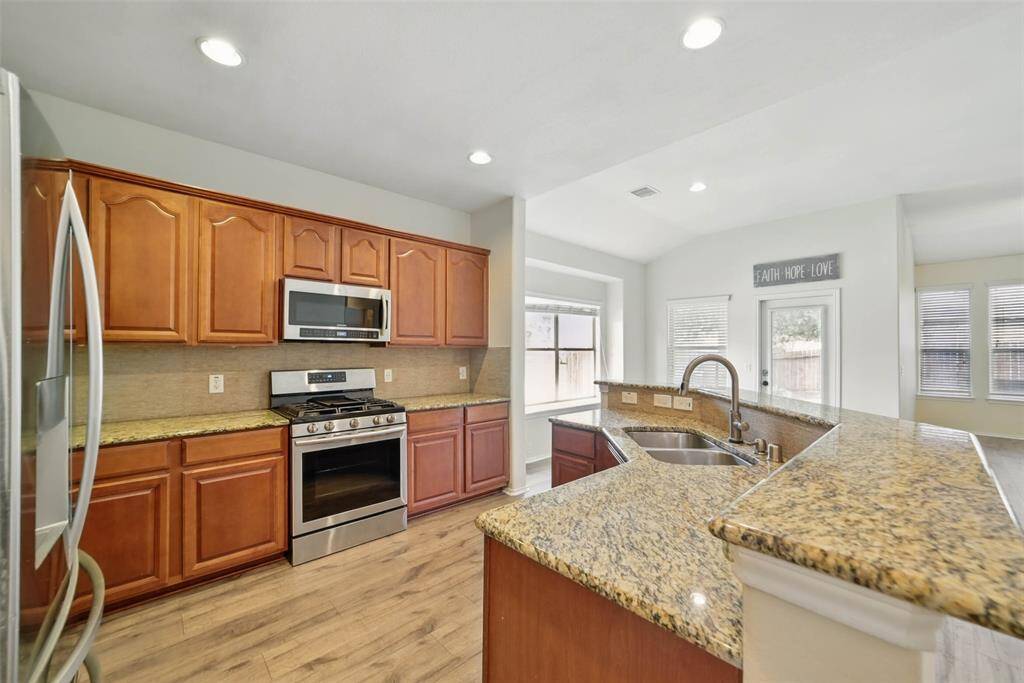 The kitchen features granite counters, stainless steel appliances, a raised breakfast bar and recent laminate flooring.