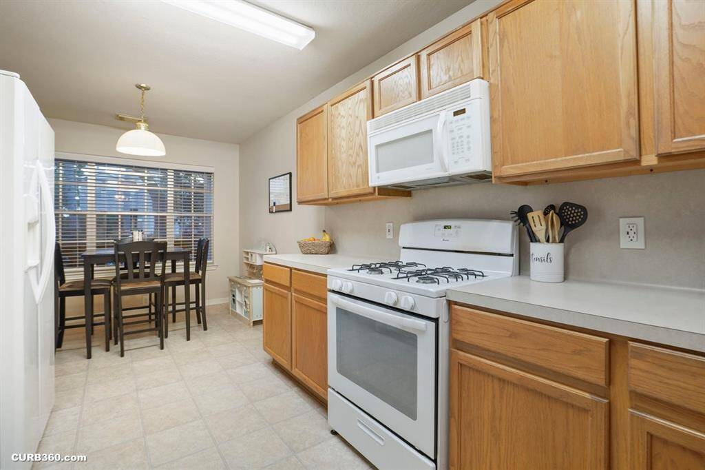 This inviting kitchen features ample cabinetry, modern appliances, and a cozy dining area by a large window, perfect for enjoying meals with natural light.