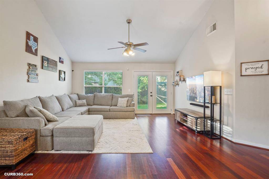 Experience spacious living in this inviting home featuring an open floor plan with high ceilings and warm wood flooring. The cozy living area seamlessly flows into a dining space, perfect for entertaining. Natural light fills the room, creating a welcoming ambiance.