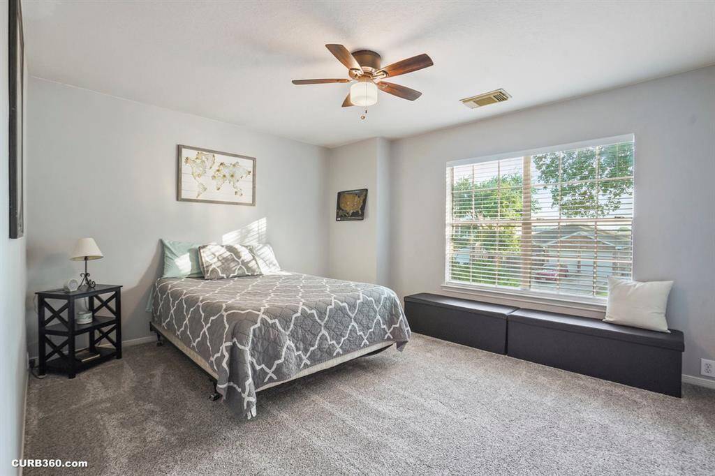 Charming nursery with cozy carpeting, ample natural light, and stylish decor. Features include a comfortable rocking chair, organized shelving, and a modern crib, creating a perfect space for your little one.