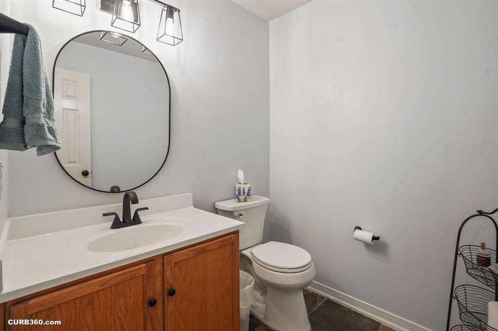 Experience modern elegance in this pristine bathroom, featuring a sleek vanity with ample storage, a stylish round mirror, and contemporary lighting.