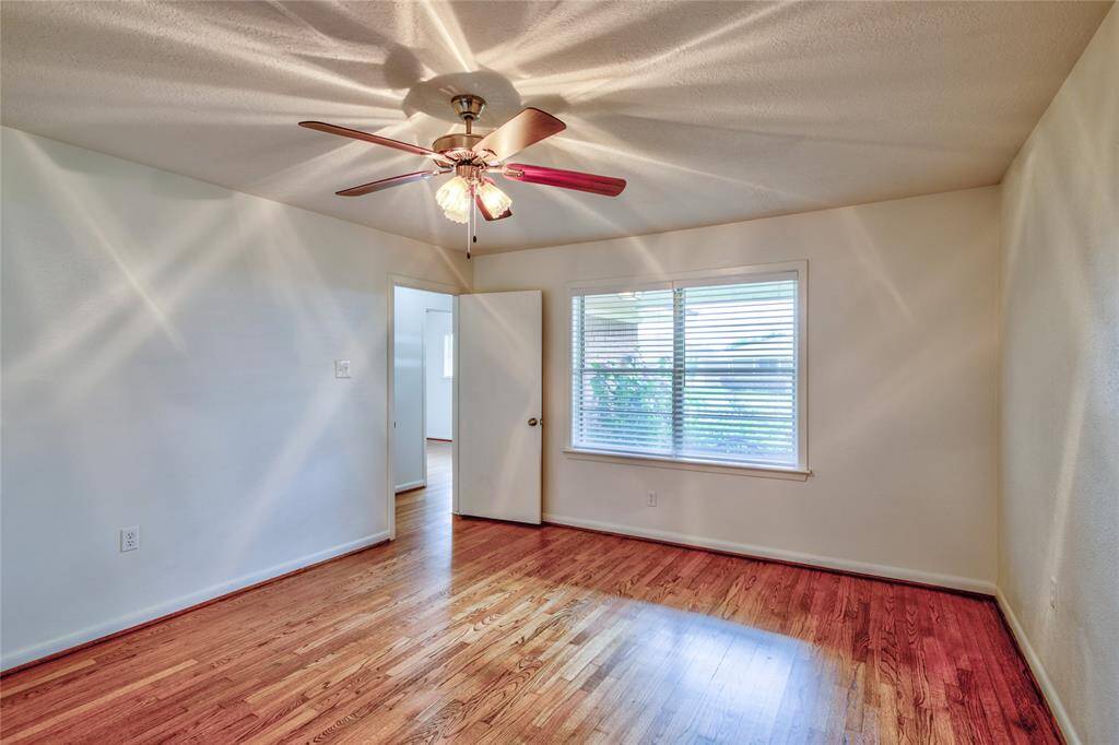 Bright and inviting front entry room with solid white oak-wood floors, a ceiling fan, and large window for natural light.