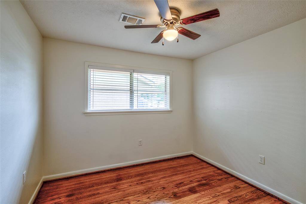 This spacious second bedroom features elegant white oak wood flooring, offering both style and comfort.