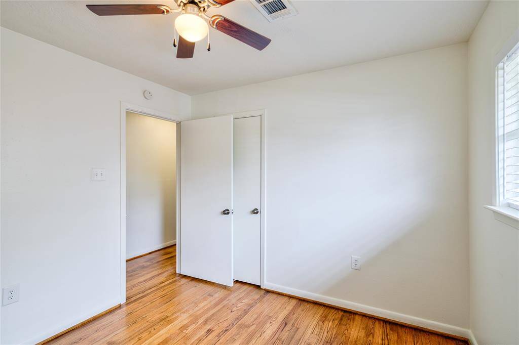 Bright and airy second bedroom with gleaming solid white oak-wood floors and ample natural light.