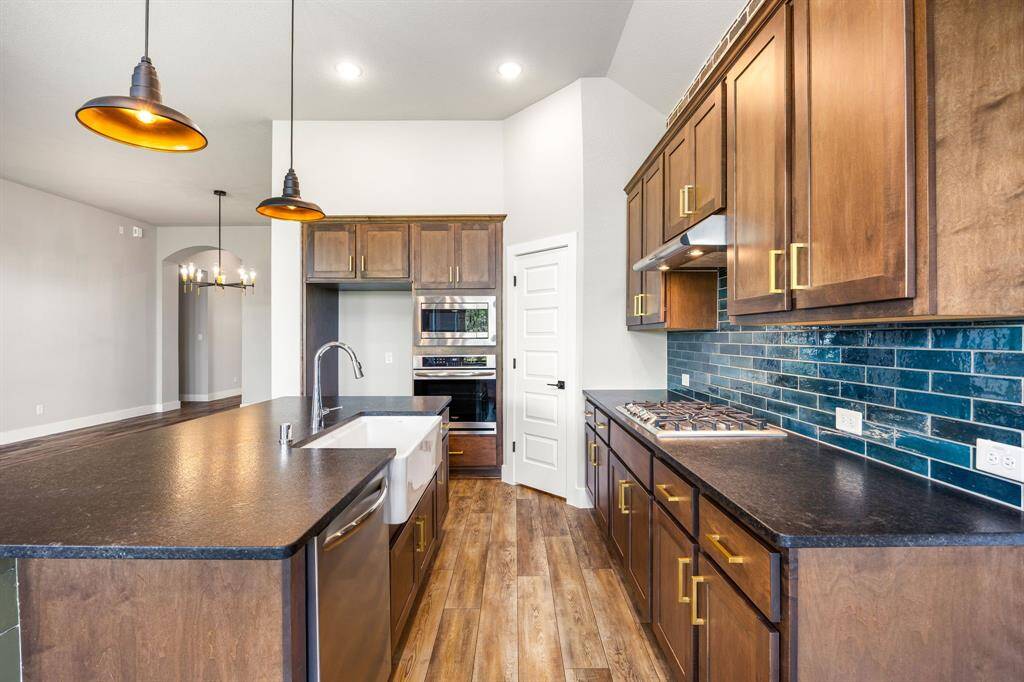 This stunning kitchen displays such a beautiful contrast with the dark stained cabinets, custom paint, Quartz countertops, modern tile backsplash, SS appliances, oversized kitchen island with extra storage, breakfast bar, recessed lighting, high ceilings and walk in pantry.