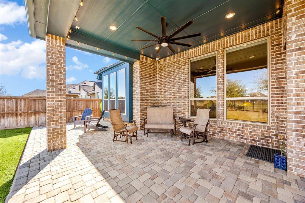 This exquisite covered patio offers the perfect blend of style and comfort, featuring a beautifully paved floor, recessed lighting, and a statement ceiling fan for year-round enjoyment. The elegant brick exterior and large windows provide a seamless transition between indoor and outdoor living. Ideal for entertaining or unwinding in a private backyard retreat.