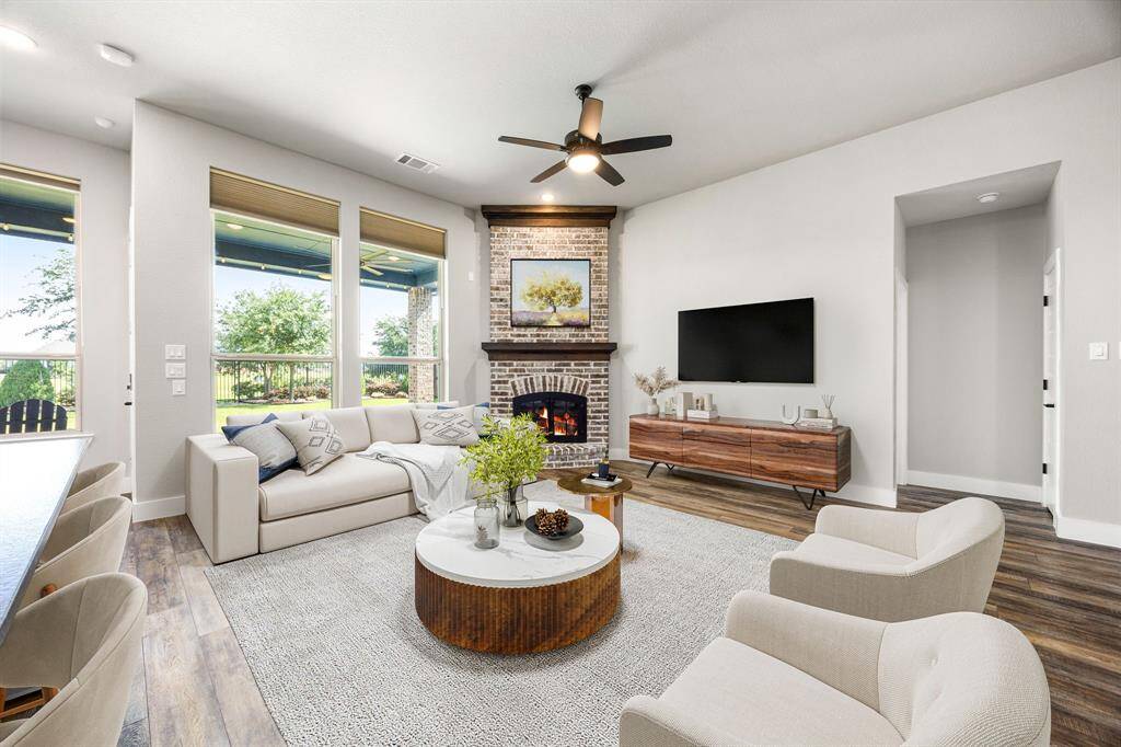 This living room is more like a GREAT room featuring a stunning brick fireplace with mantel detailing, custom paint, soaring ceiling, dark stained ceiling fan, and an amazing wall of windows providing a lovely view of your backyard to keep an eye out on the kids or pets playing.