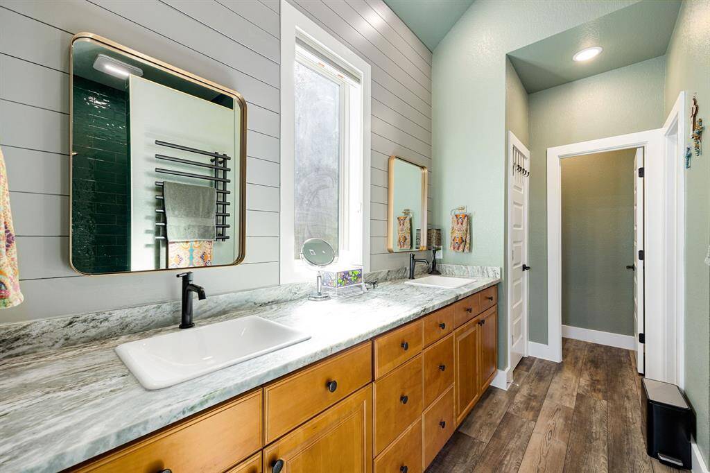 This primary bathroom is definitely move-in ready! Featuring shiplap detail, warm wood cabinets with Quartz countertops, spacious custom walk-in closet with shelving, high ceilings, custom paint, sleek and modern finishes.