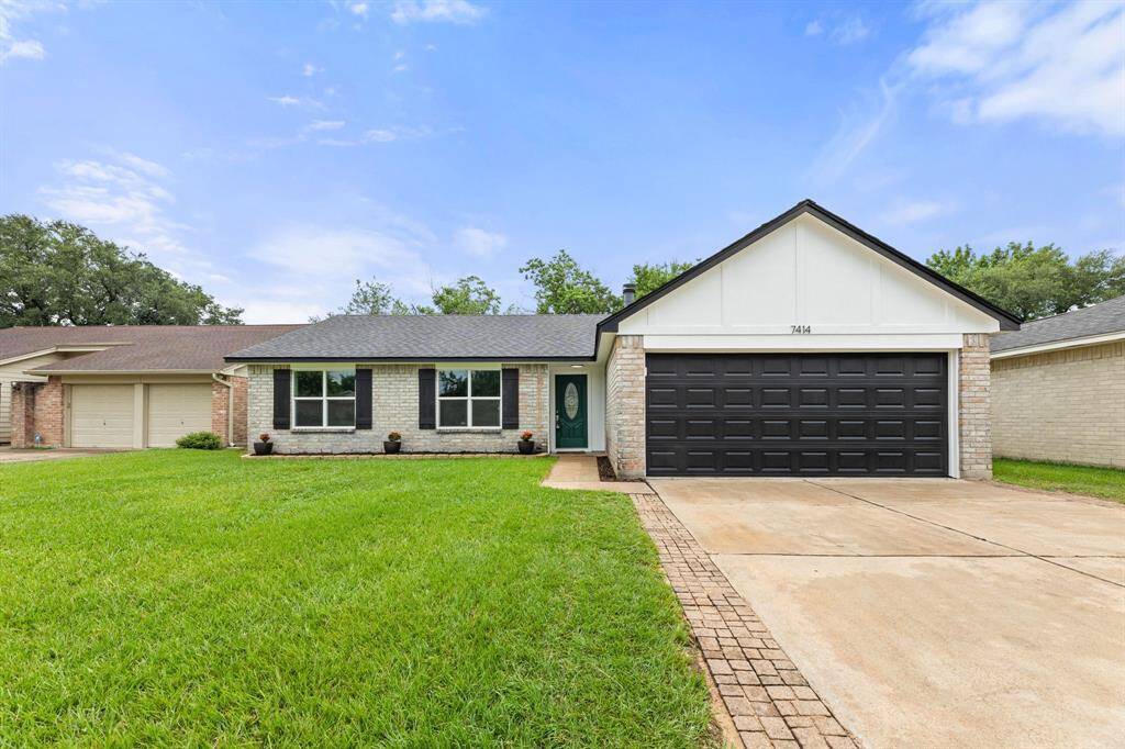 This is a charming single-story home with a brick exterior, featuring a double garage with a dark door. It has a well-maintained front lawn and a welcoming entrance with a decorative glass door.