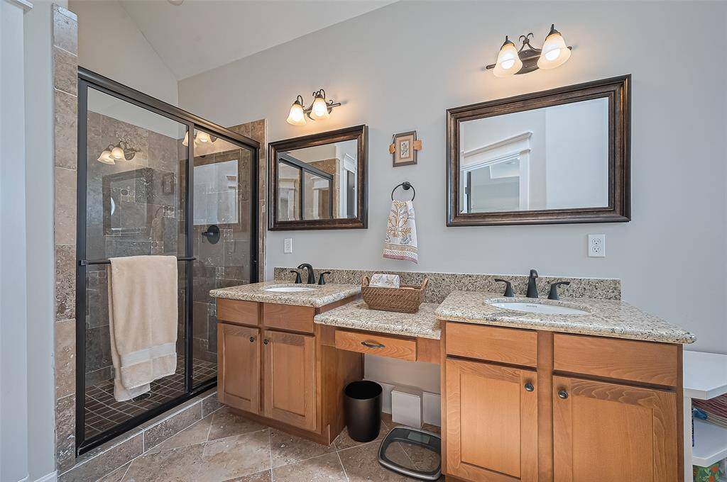 Primary bathroom with double sinks, stand along shower and granite countertops