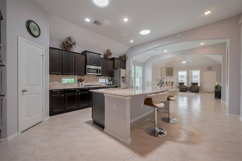 The island kitchen boasts granite countertops, rich cabinetry, stainless steel appliances, and a breakfast bar—all open to the spacious dining area for effortless entertaining.