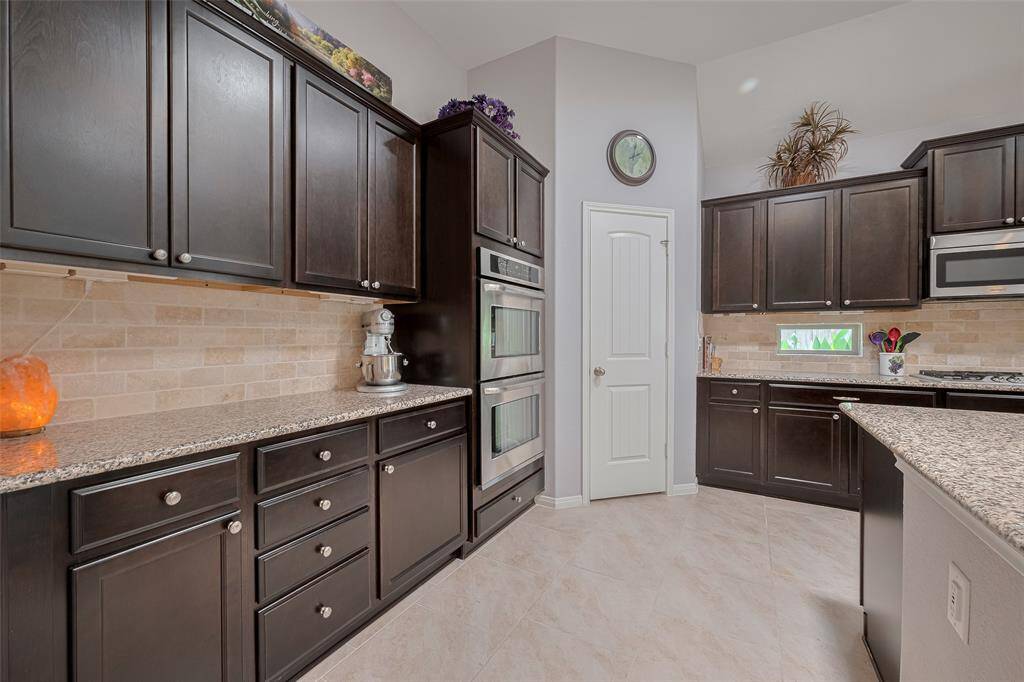 Custom cabinetry and granite countertops offer abundant storage and prep space, while the built-in double ovens make multitasking effortless.