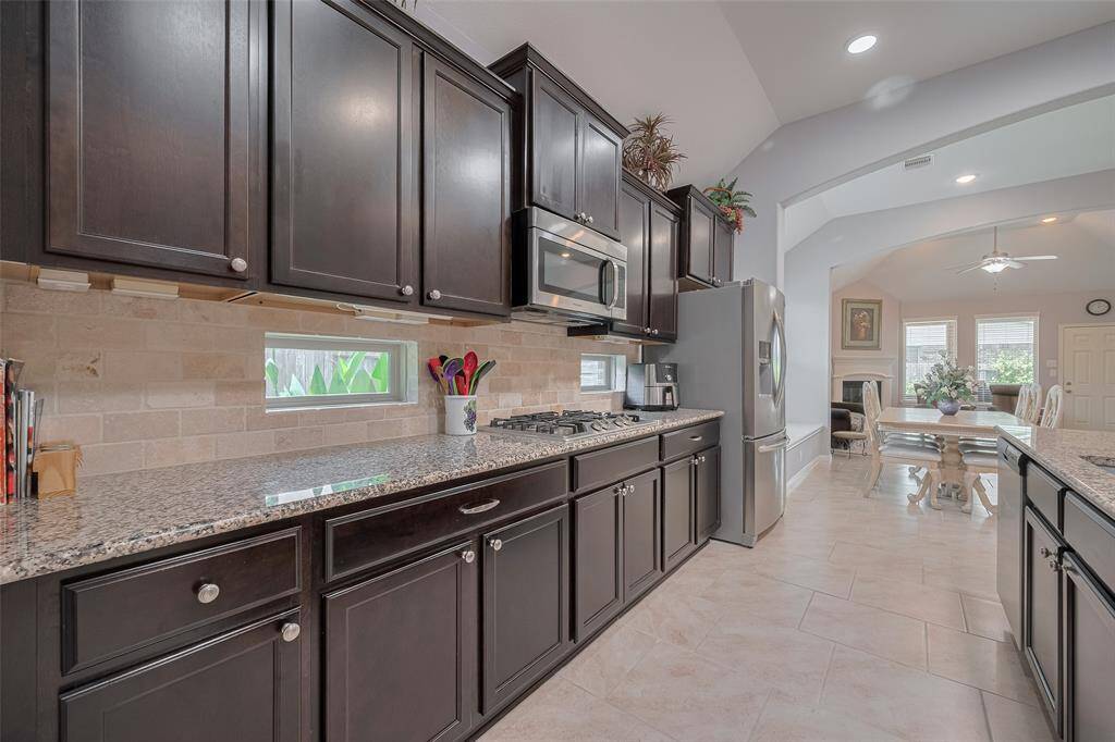 A wall of upper and lower cabinets, framed by under-cabinet lighting and stylish brick backsplash, ensures form meets function at every turn.