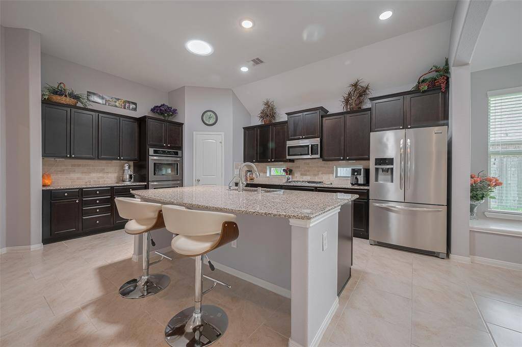 The oversized island provides extra workspace and a secondary prep sink, with bar seating perfect for casual bites or morning coffee.