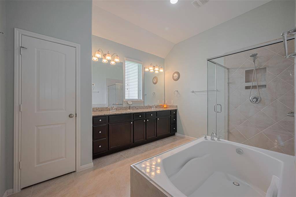 A long granite vanity with dual sinks offers ample counter space and makes busy mornings a breeze.