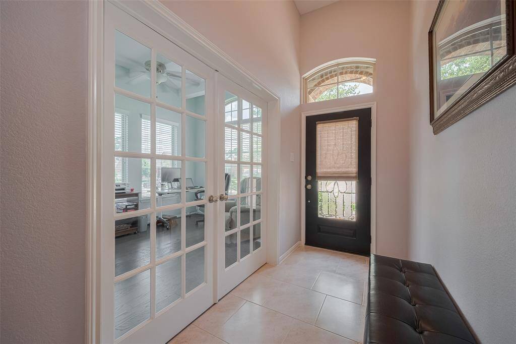 A warm and inviting entryway welcomes you inside, where glass French doors offer a glimpse into the private home office just off the foyer.