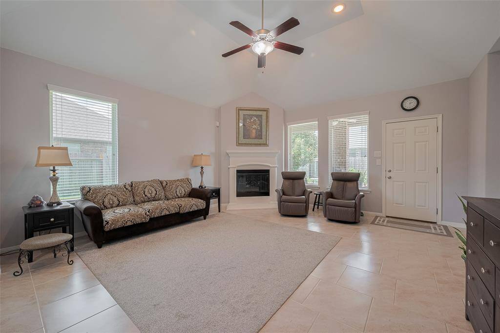 The spacious family room features a cozy fireplace, vaulted ceilings, and a wall of windows for beautiful natural light—an ideal setting for everyday living or entertaining.