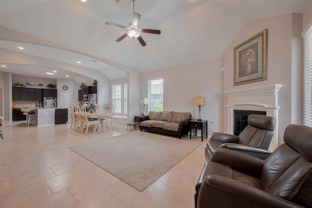 Elegant archways and a soaring ceiling add architectural interest to this open-concept layout, where the fireplace anchors the living space and large windows offer backyard views.