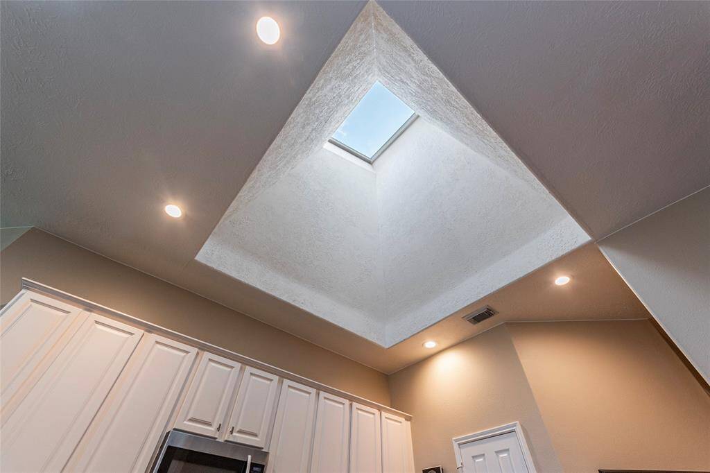 This photo showcases the kitchen ceiling with a 22 foot skylight and recessed lighting.