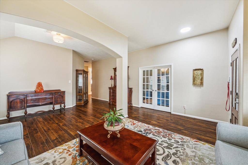 This home office features a  large window overlooking the front yard, a stylish chandelier that adds elegance and a walk in closet with shelving. French doors provide privacy. Could be a 5th bedroom.
