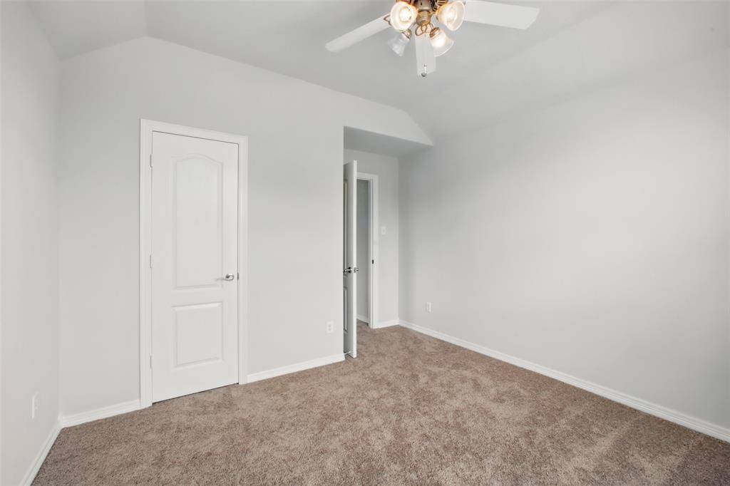 This additional upstairs bedroom features plush carpet, a neutral color scheme, and a ceiling fan with lighting. The layout is functional and flexible—perfect for a guest room, nursery, or home office. A standard closet provides convenient storage, and the natural light helps keep the space feeling open and inviting.